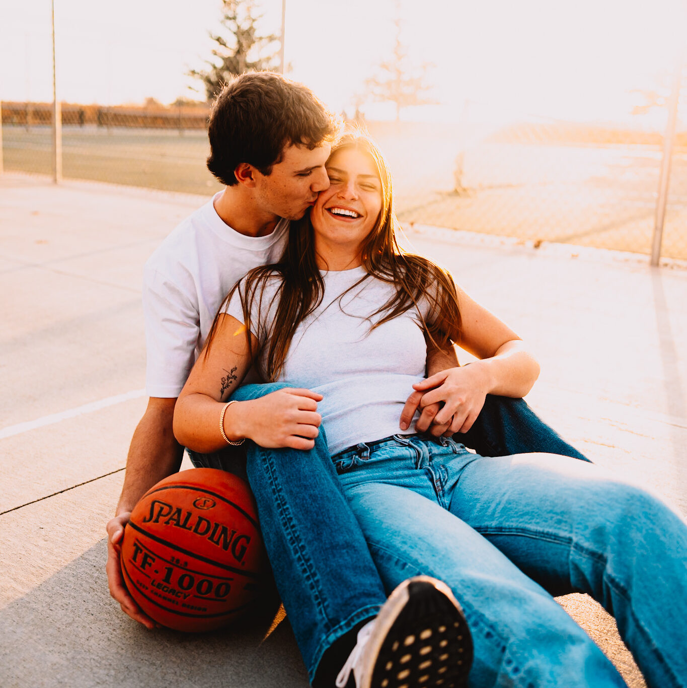 couple laughing on basketball court during Minnesotas golden hour